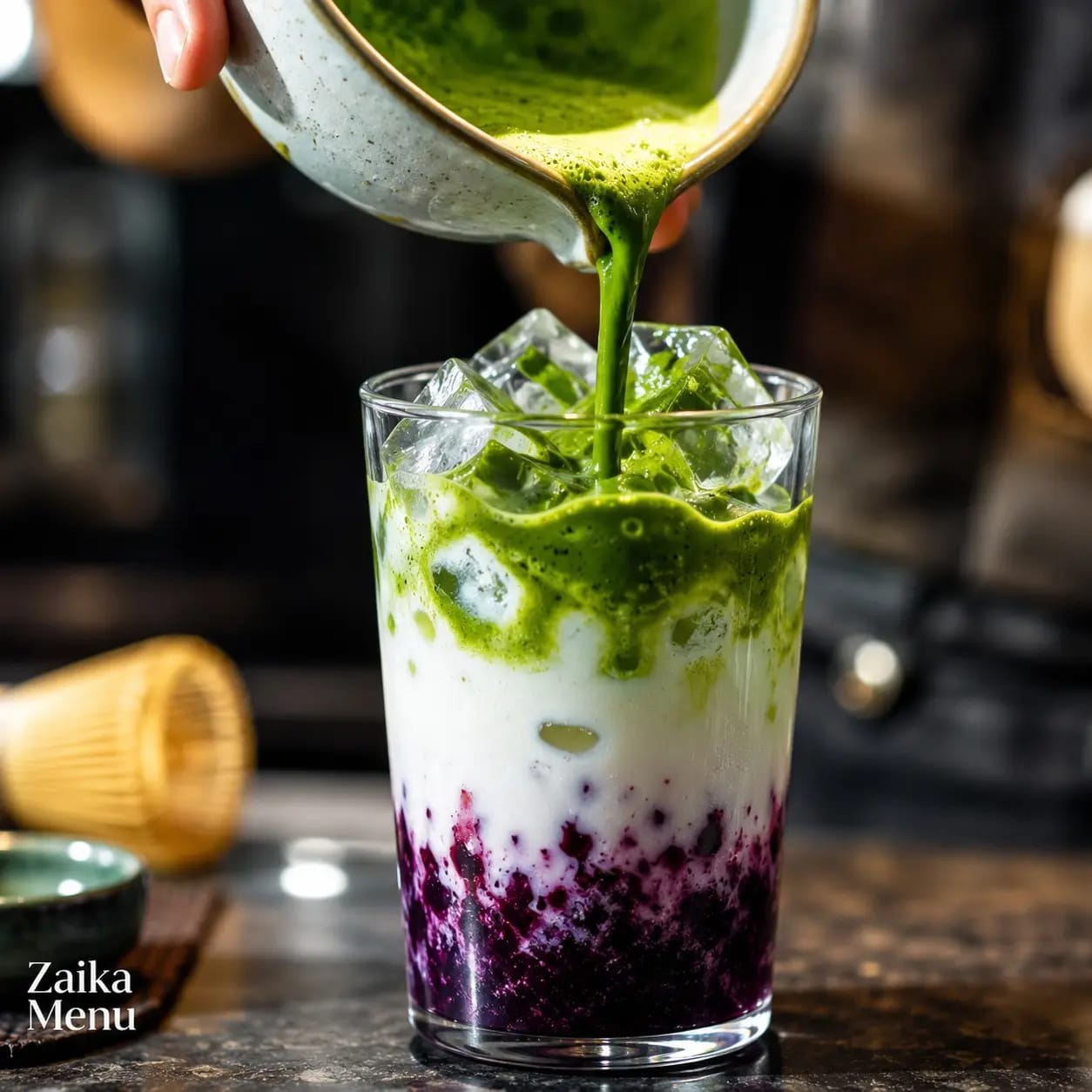 Barista pouring neon green tea foam over iced blueberry milk