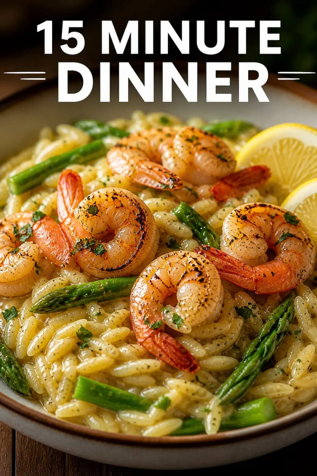 A steaming bowl of creamy lemon garlic shrimp and orzo with fresh asparagus and lemon slices.
